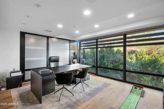 office featuring a wall of windows, recessed lighting, light wood-style floors, and visible vents