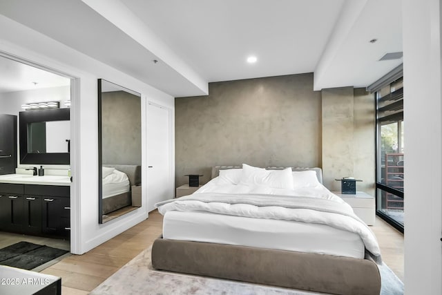 bedroom featuring visible vents, light wood-style flooring, recessed lighting, a sink, and connected bathroom