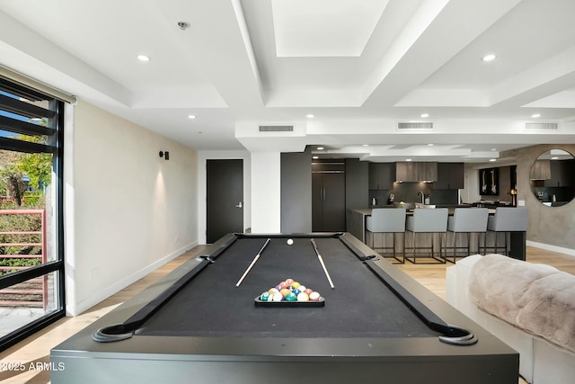 rec room featuring visible vents, a raised ceiling, and light wood-style floors