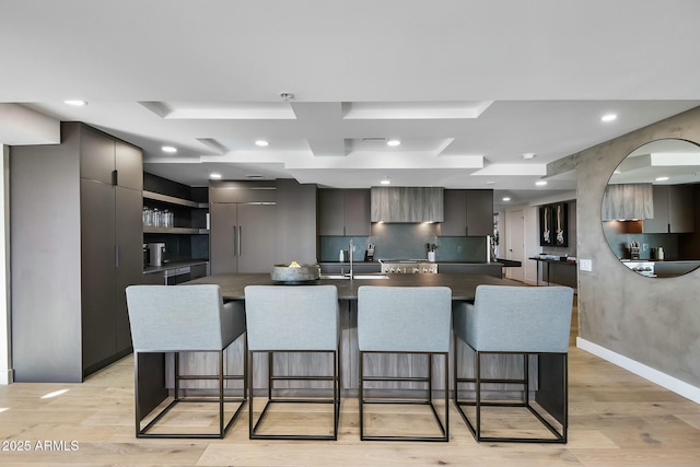 kitchen with paneled fridge, modern cabinets, light wood-type flooring, and a breakfast bar