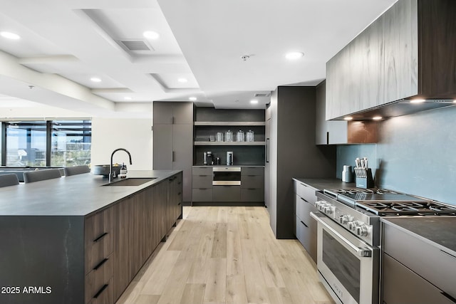 kitchen featuring dark countertops, visible vents, high end stainless steel range oven, modern cabinets, and a sink