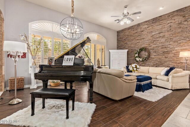 living area featuring ceiling fan with notable chandelier, baseboards, and wood finished floors