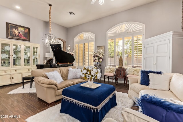 living area featuring ceiling fan with notable chandelier, dark wood-style floors, and visible vents