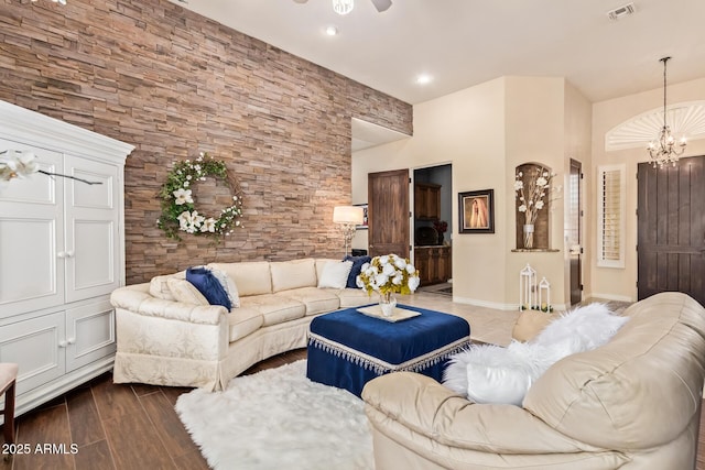 living room with ceiling fan with notable chandelier, visible vents, dark wood-style flooring, and baseboards