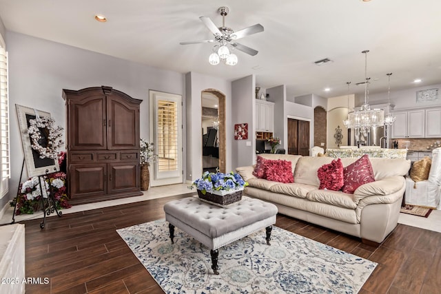 living room featuring visible vents, ceiling fan with notable chandelier, recessed lighting, arched walkways, and dark wood-style flooring