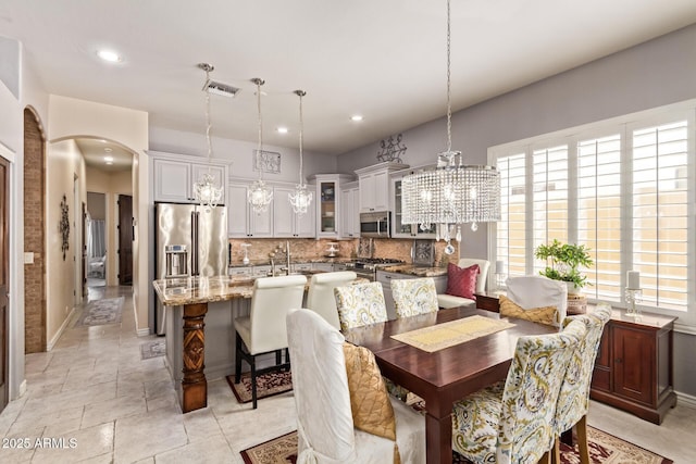 dining space featuring visible vents, baseboards, a chandelier, recessed lighting, and arched walkways