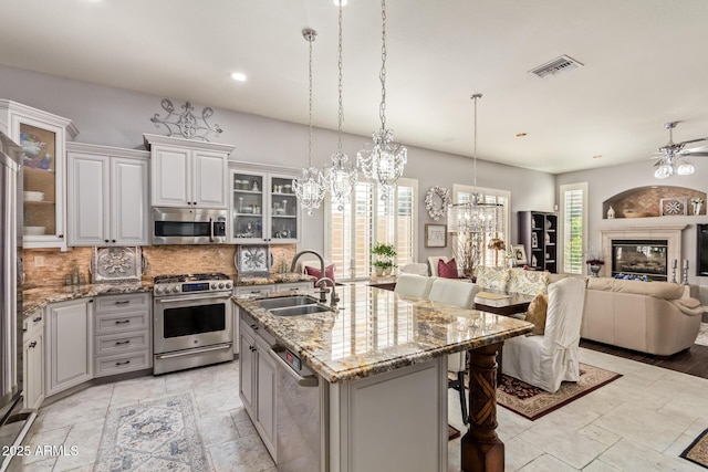 kitchen with visible vents, stainless steel appliances, open floor plan, and a sink