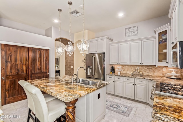 kitchen with visible vents, light stone countertops, decorative backsplash, appliances with stainless steel finishes, and a sink