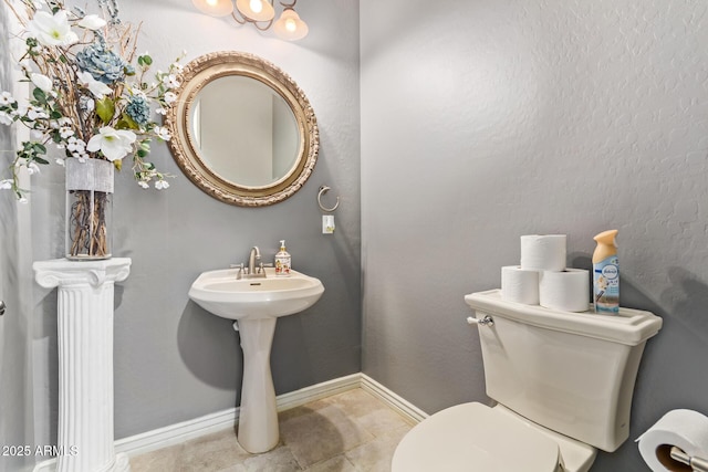 bathroom featuring baseboards, toilet, and tile patterned flooring