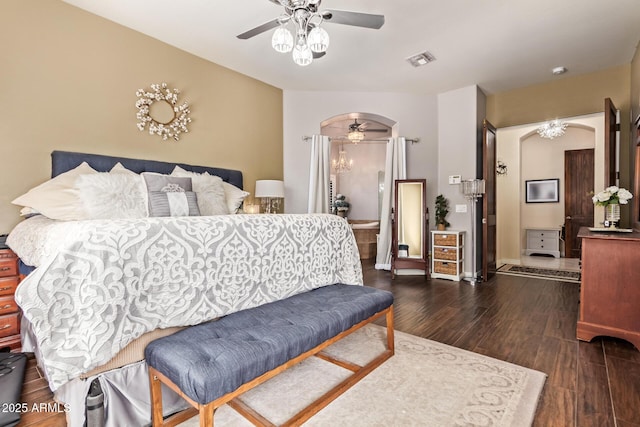 bedroom with visible vents, baseboards, dark wood finished floors, arched walkways, and a ceiling fan