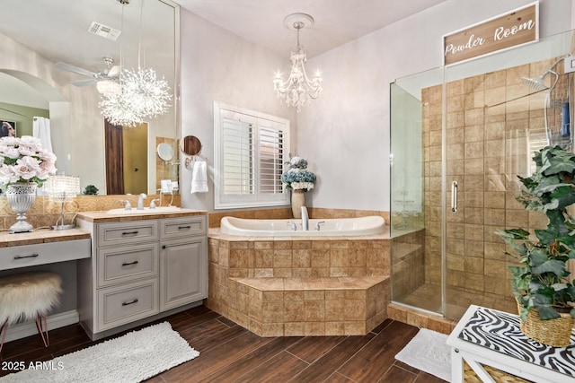 bathroom with vanity, wood tiled floor, a shower stall, a garden tub, and ceiling fan with notable chandelier