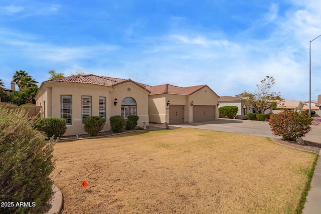 mediterranean / spanish-style home featuring a front lawn, a tiled roof, concrete driveway, stucco siding, and an attached garage