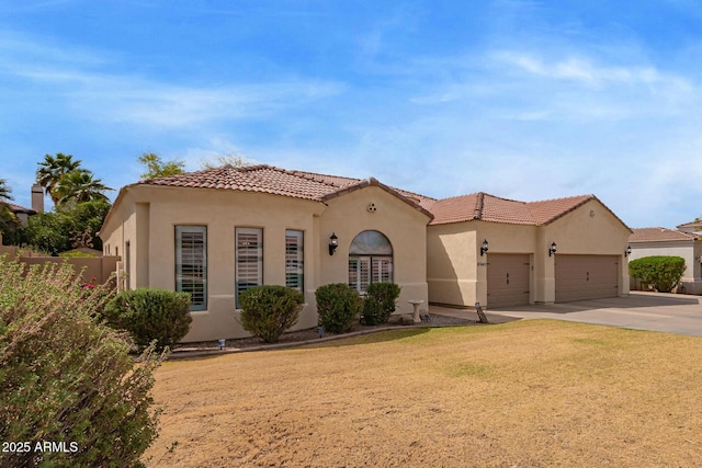 mediterranean / spanish home with stucco siding, a front lawn, a tile roof, concrete driveway, and an attached garage