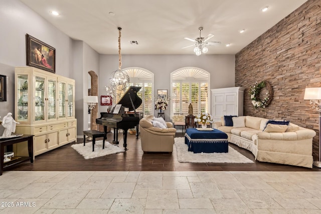 living area with visible vents, ceiling fan with notable chandelier, stone tile flooring, recessed lighting, and a high ceiling