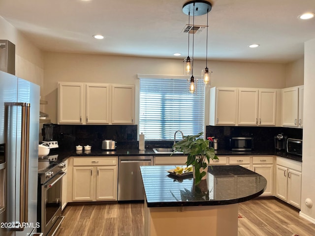 kitchen featuring appliances with stainless steel finishes, pendant lighting, sink, white cabinets, and light hardwood / wood-style flooring