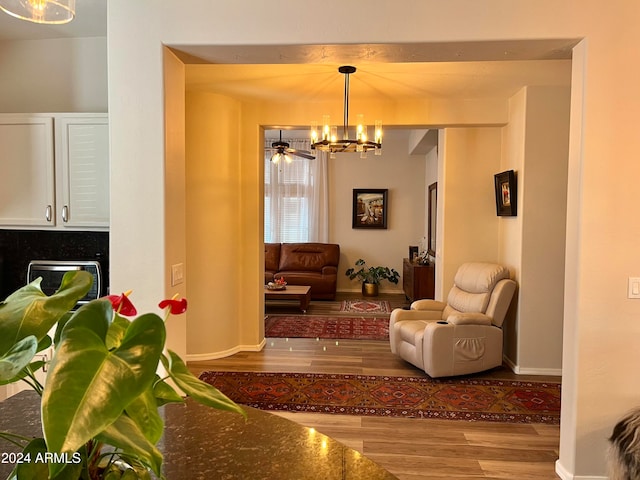 living room with ceiling fan with notable chandelier and light hardwood / wood-style floors