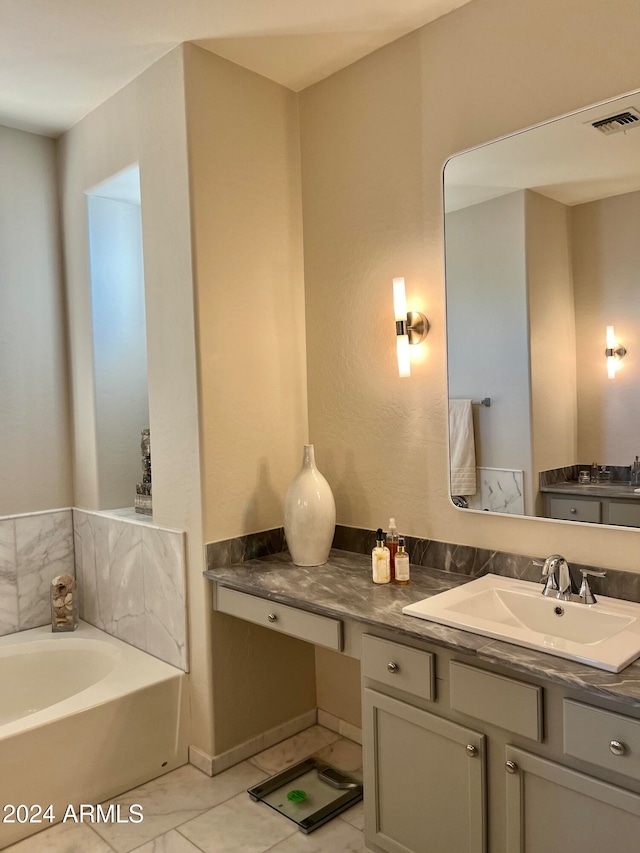 bathroom with a tub to relax in, vanity, and tile patterned floors