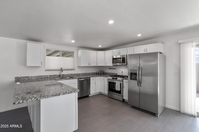 8425 E Hawthorne St, Tucson, AZ 85710 - kitchen with stainless steel appliances, dark stone counters, white cabinetry, a peninsula, and baseboards