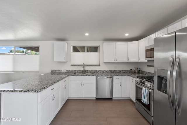 8425 E Hawthorne St, Tucson, AZ 85710 - kitchen with appliances with stainless steel finishes, a sink, a peninsula, white cabinets, and dark stone countertops