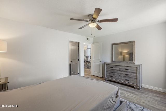 bedroom featuring wood finished floors, visible vents, baseboards, and ceiling fan