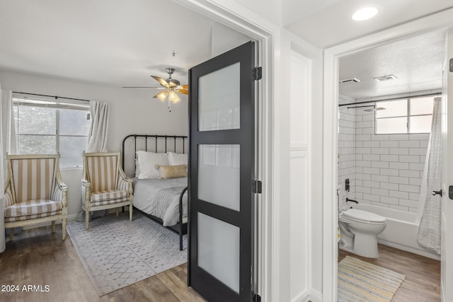 bedroom with baseboards, wood finished floors, connected bathroom, and multiple windows