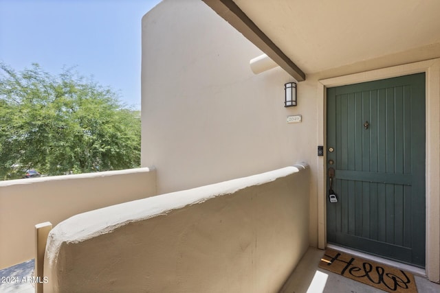 view of exterior entry with a balcony and stucco siding