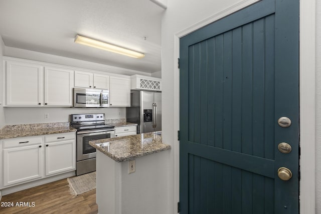 kitchen with light stone counters, white cabinetry, appliances with stainless steel finishes, and dark wood finished floors