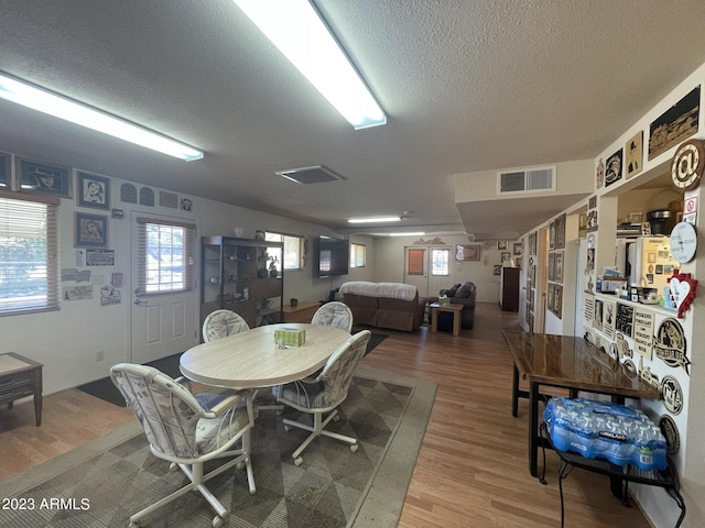 dining space with wood-type flooring and a textured ceiling