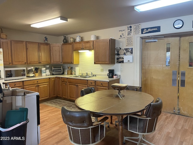 kitchen with sink, decorative backsplash, and light hardwood / wood-style flooring