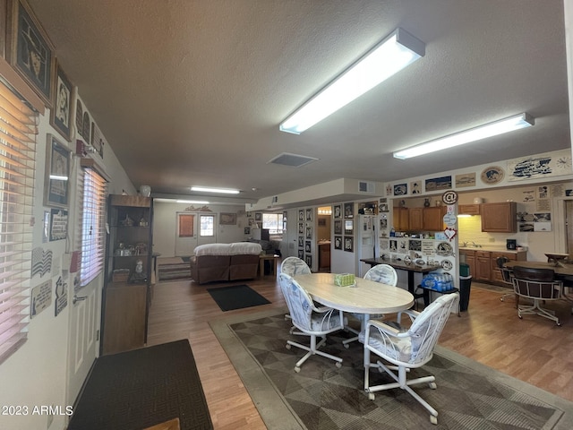 dining space with hardwood / wood-style floors and a textured ceiling