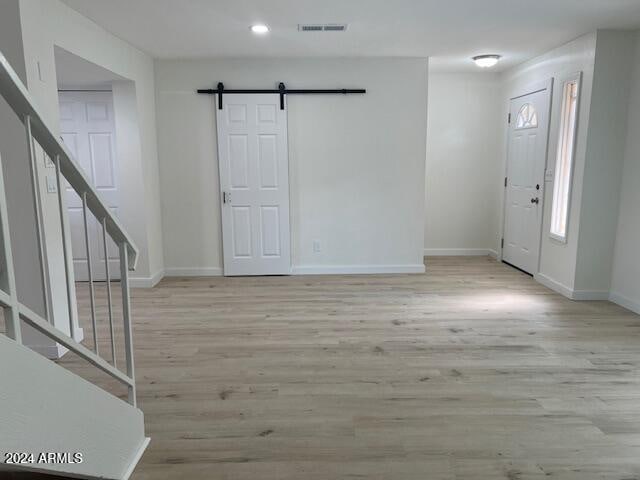 foyer entrance with light wood-type flooring and a barn door