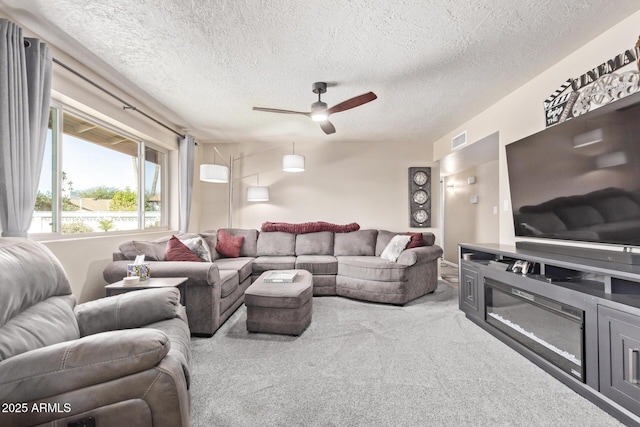 living room with a textured ceiling, ceiling fan, and light colored carpet