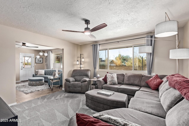 living room featuring a textured ceiling, ceiling fan, and light tile patterned floors