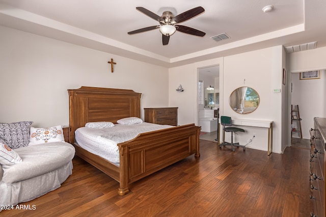 bedroom featuring dark wood-type flooring, a raised ceiling, ceiling fan, and ensuite bath