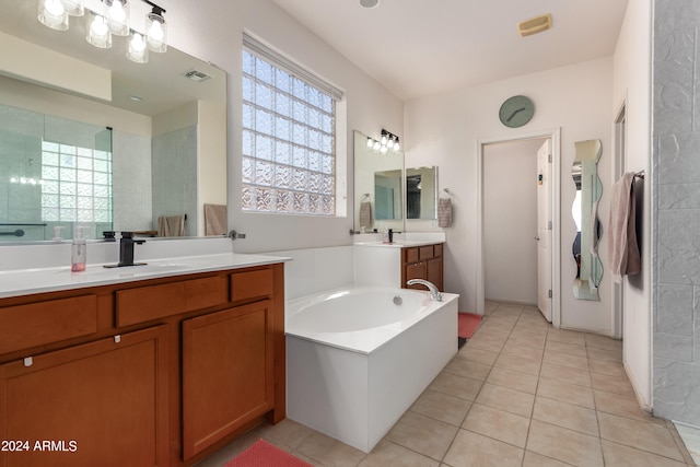 bathroom with a wealth of natural light, vanity, a tub to relax in, and tile patterned floors