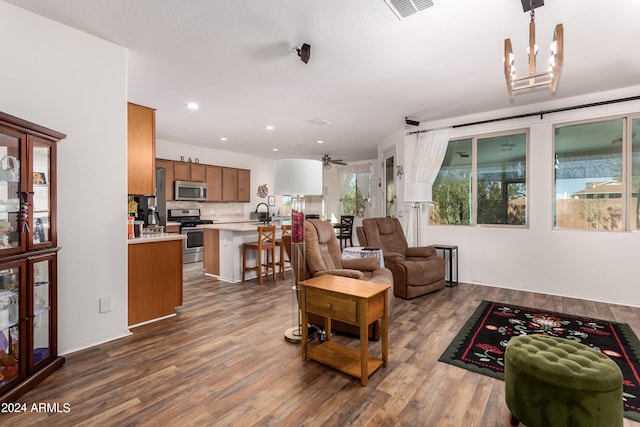 living room featuring dark wood-type flooring, sink, and ceiling fan with notable chandelier