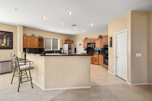 kitchen featuring dark countertops, recessed lighting, visible vents, a peninsula, and black appliances