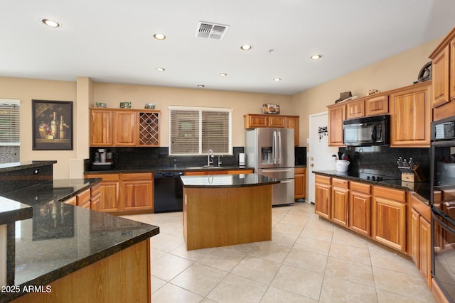 kitchen with visible vents, decorative backsplash, a kitchen island, a sink, and black appliances