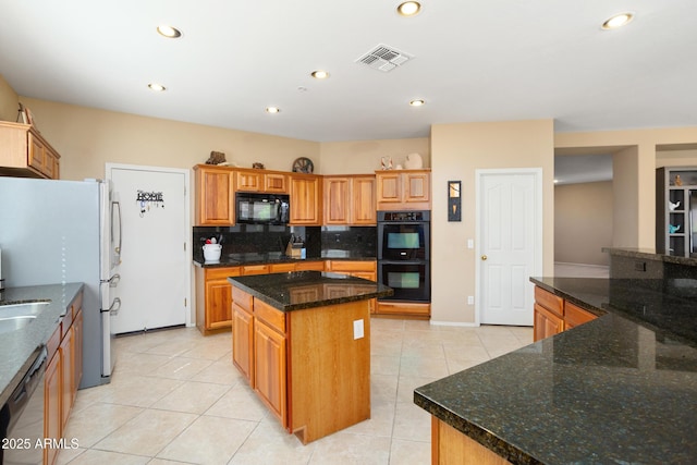 kitchen featuring light tile patterned floors, visible vents, decorative backsplash, a center island, and black appliances