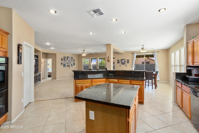 kitchen with black dishwasher, light tile patterned flooring, a kitchen island, and visible vents