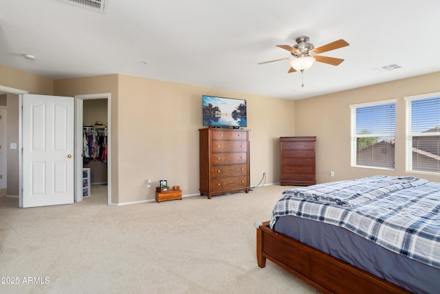 carpeted bedroom featuring a ceiling fan, visible vents, a spacious closet, and baseboards