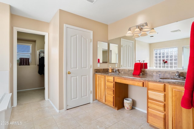 bathroom featuring tile patterned flooring, a sink, baseboards, and double vanity