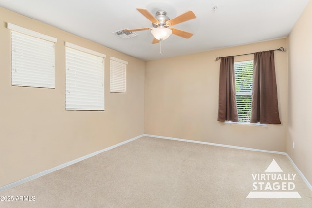 carpeted spare room featuring baseboards, visible vents, and a ceiling fan