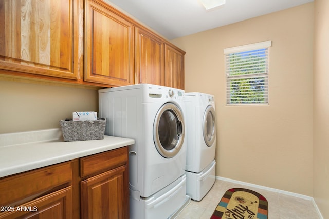 washroom with light tile patterned floors, washer and clothes dryer, cabinet space, and baseboards