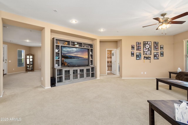 carpeted living area with ceiling fan and baseboards