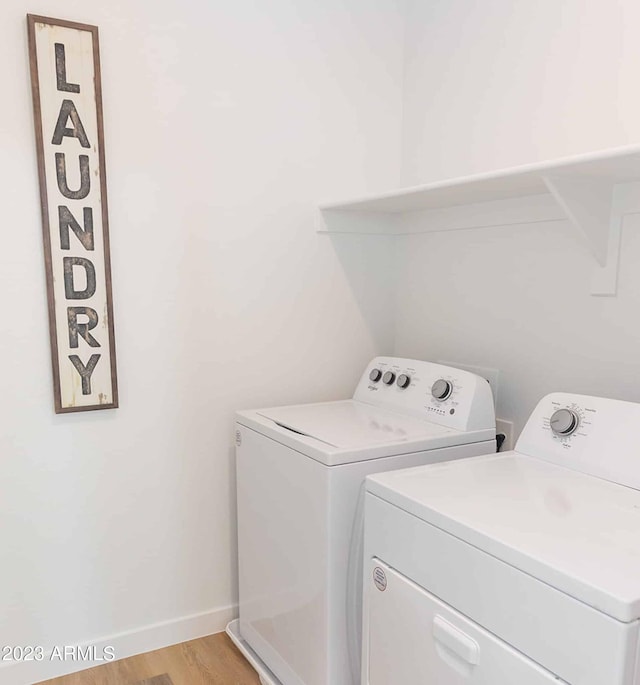 clothes washing area featuring washing machine and dryer and light wood-type flooring