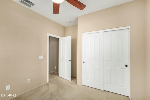 unfurnished bedroom featuring a closet, light colored carpet, and ceiling fan