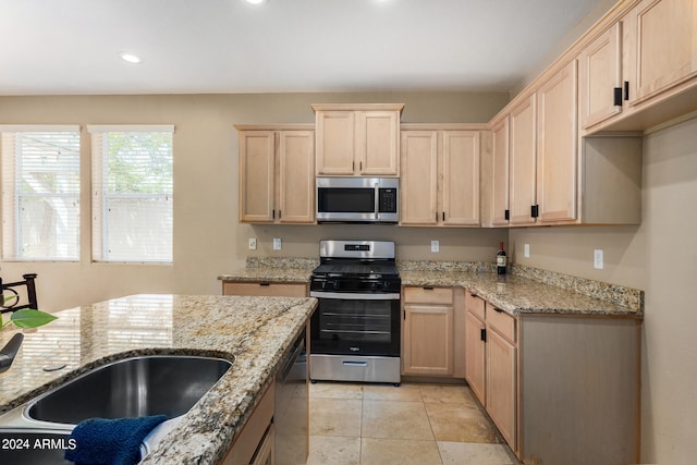 kitchen featuring light tile patterned flooring, light brown cabinetry, stainless steel appliances, and light stone counters