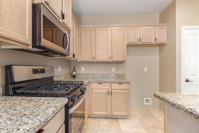 kitchen with light brown cabinetry, light tile patterned floors, stainless steel appliances, and light stone counters