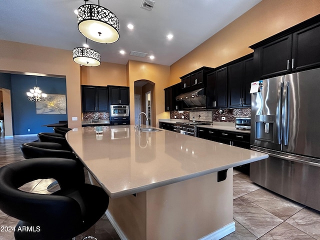 kitchen with appliances with stainless steel finishes, tasteful backsplash, hanging light fixtures, and a spacious island